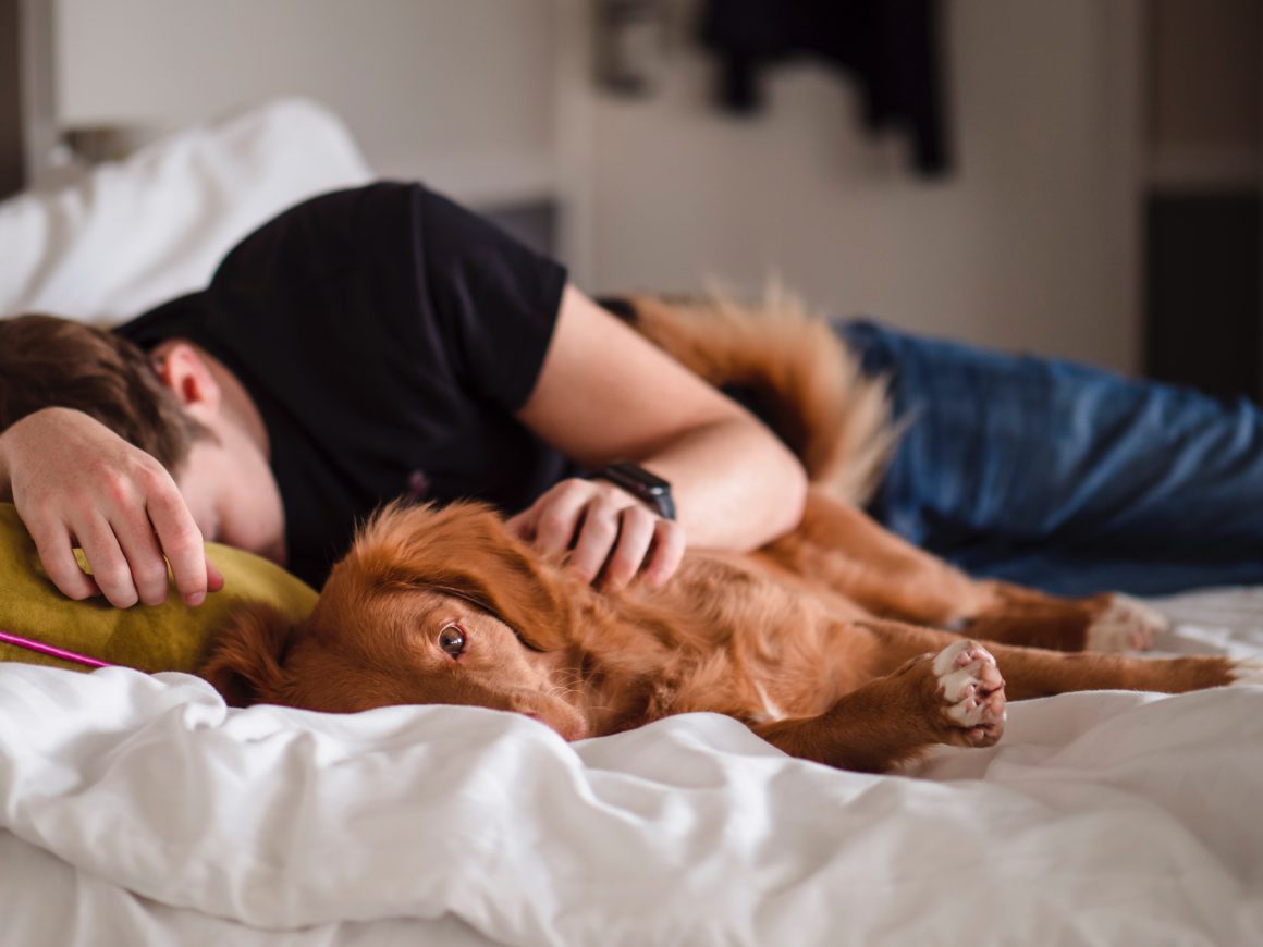man laying in bed with dog